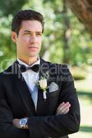 Thoughtful groom with arms crossed in garden