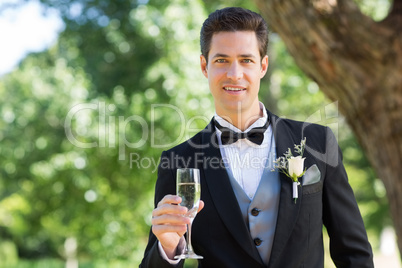 Groom holding champagne flute in garden