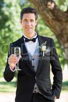Sophisticated groom holding champagne flute in garden