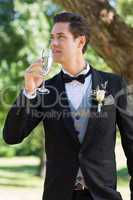 Thoughtful bridegroom drinking champagne