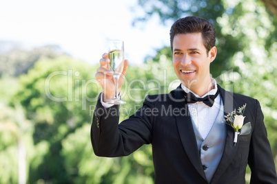 Groom toasting champagne flute in garden