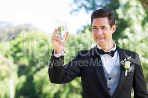 Groom toasting champagne flute in garden