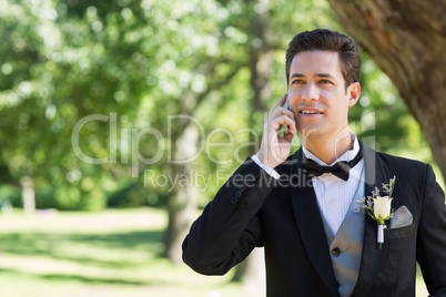 Groom using cellphone in garden