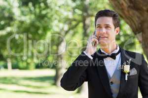 Groom using cellphone in garden