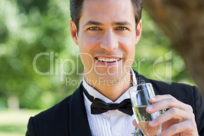 Young groom drinking champagne in garden