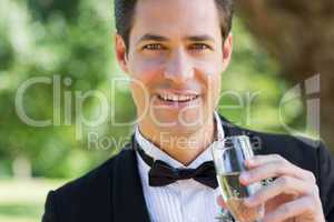 Young groom drinking champagne in garden