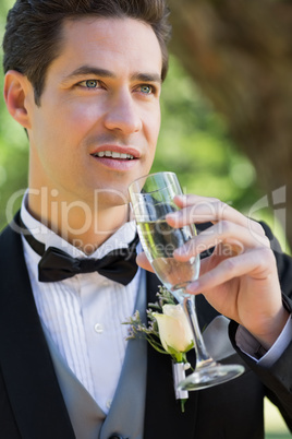 Thoughtful groom drinking champagne