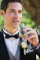 Thoughtful groom drinking champagne