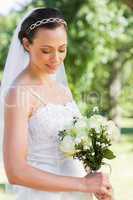 Shy bride holding flower bouquet in garden