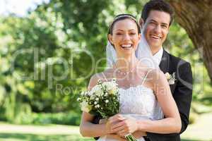 Newly wed couple with flower bouquet in park