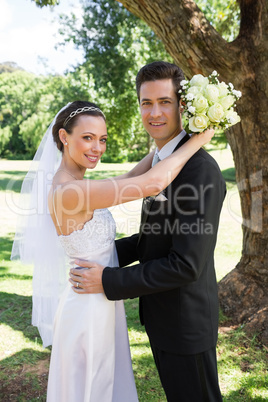Bride and groom embracing in garden