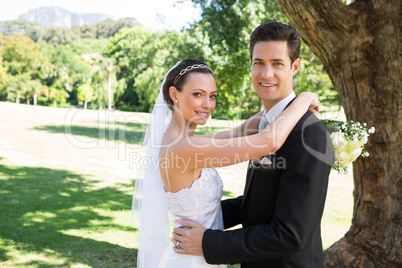 Smiling bride and groom embracing in garden