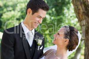 Bride and groom looking at each other in garden