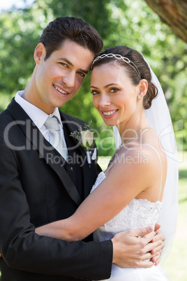 Young bride and groom hugging in garden