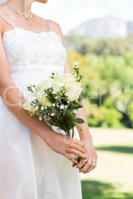 Midsection of bride holding bouquet in garden