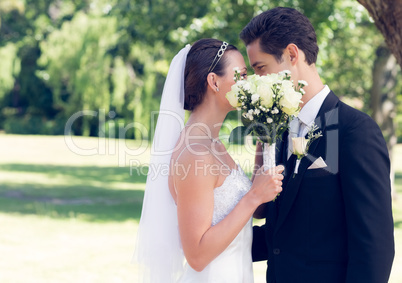 Couple kissing behind bouquet in garden