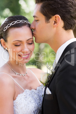 Groom kissing bride on head in garden