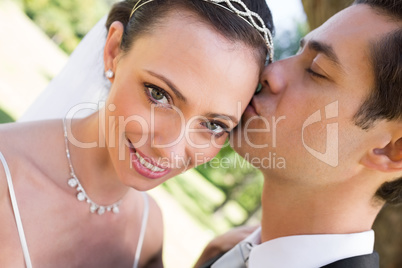 Bride being kissed by groom in garden