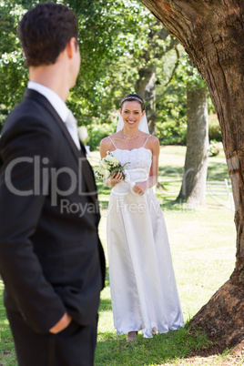 Happy bride looking at groom in garden