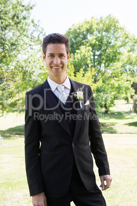 Groom in tuxedo standing at garden