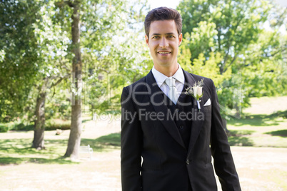 Confident groom smiling in garden