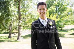 Confident groom smiling in garden