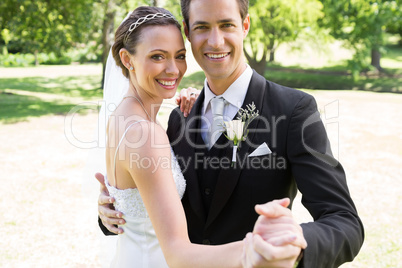 Happy bride and groom dancing together in garden