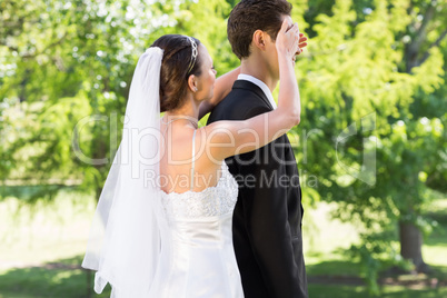 Young bride covering eyes of groom in garden