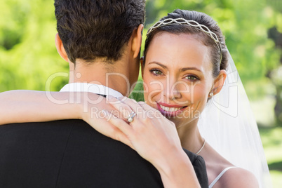 Beautiful bride embracing groom in garden