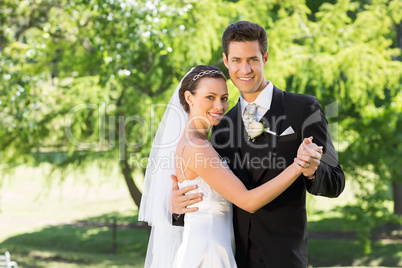 Smiling bride and groom dancing in garden