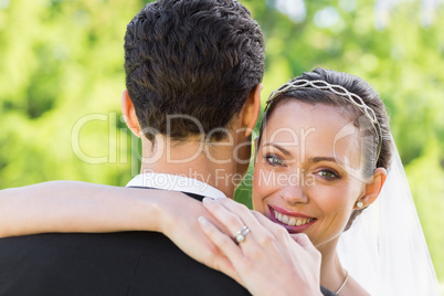 Portrait of happy bride embracing groom