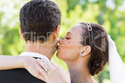 Young bride kissing groom on cheek