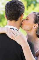 Closeup of bride kissing groom on cheek