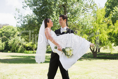 Groom carrying bride in arms at garden