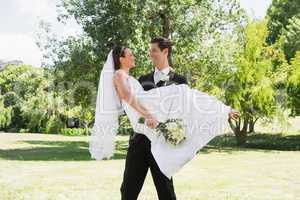 Groom carrying bride in arms at garden