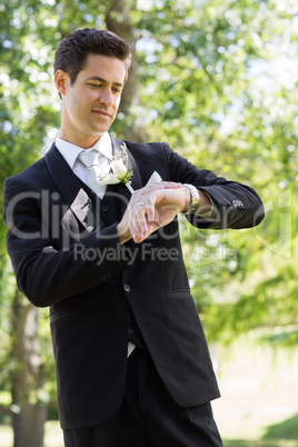 Bridegroom checking time in garden