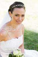 Bride sitting on grass in garden