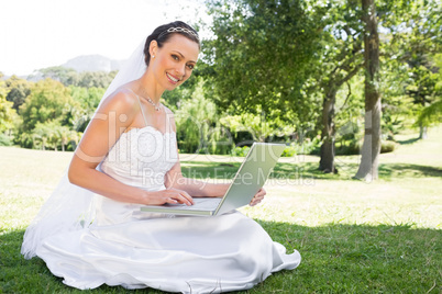 Beautiful bride using laptop in garden