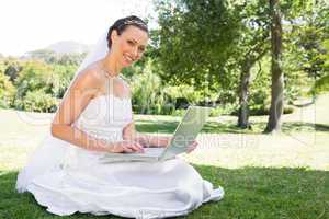 Beautiful bride using laptop in garden