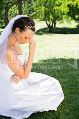 Female bride sitting on grass in park