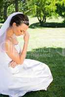 Female bride sitting on grass in park