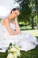 Sad bride with hand on chin in garden