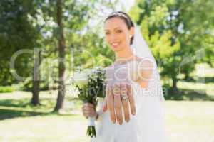 Beautiful bride showing wedding ring in garden