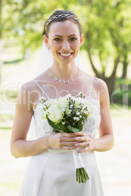 Woman in wedding gown holding bouquet in garden