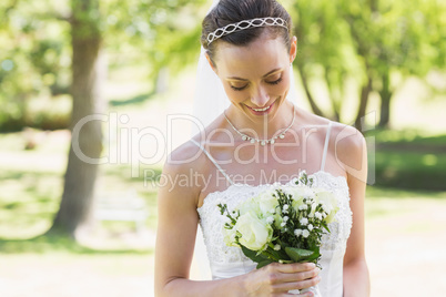 Bride looking at bouquet in garden