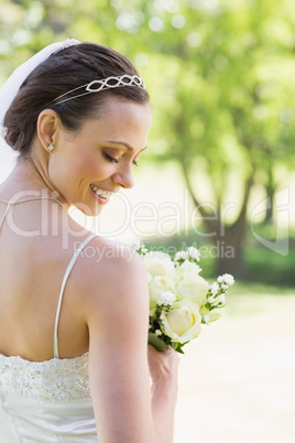Rear view of shy bride with flowers in garden