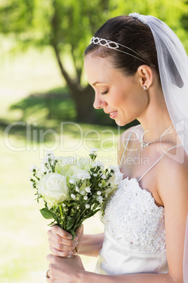 Shy bride holding bouquet in garden