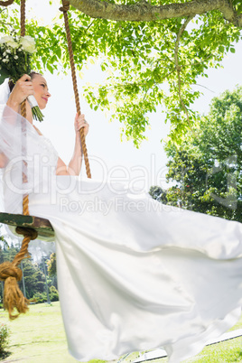 Thoughtful bride swinging in garden