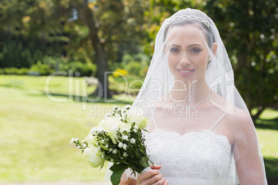 Bride smiling through veil in garden