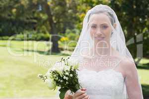 Bride smiling through veil in garden